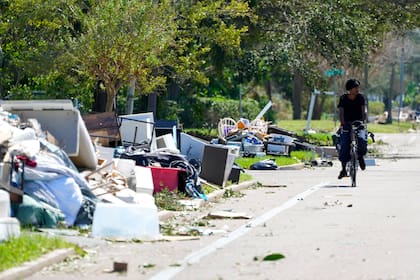 Un ciclista pasa al lado de escombros y artículos de viviendas dañados en St. Petersburg, Florida, un día después del paso del huracán Milton por la región, el jueves 10 de octubre de 2024. (AP Foto/Julio Cortez)