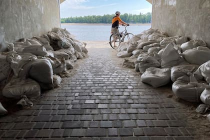 Un ciclista sale de un túnel protegido con sacos terreros cerca del río Dnipro en Kiev, Ucrania, el domingo 10 de julio de 2022. (AP Foto/Cara Anna)