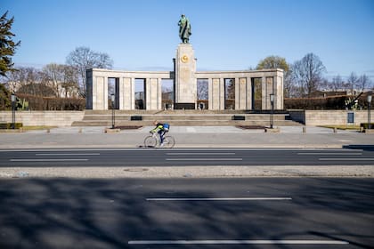 Un ciclista solitario pasa pedaleando por el Soviet War Memorial Tiergarten a lo largo de una calle casi desierta en Berlín el 1 de abril de 2020 mientras Alemania continúa su batalla contra el coronavirus