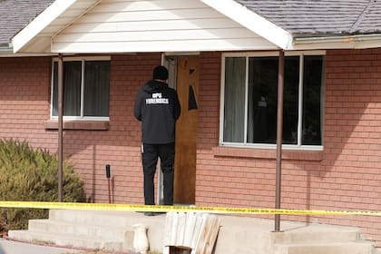 Un científico forense ingresa a una casa donde se encontró el cadáver de una mujer, en Lyman, Utah,