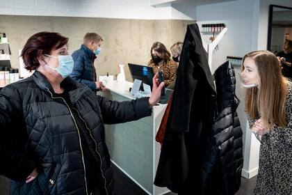 Un cliente muestra su celular con un resultado negativo de la prueba de coronavirus en una peluquera en Koege, Dinamarca