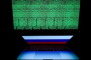 Un código digital en una pantalla ante un ordenador portátil con una bandera de Rusia.