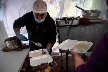 Un colaborador del comedor social Las guerreras ayuda a servir los almuerzos preparados en Santiago de Chile, el 17 de julio de 2020