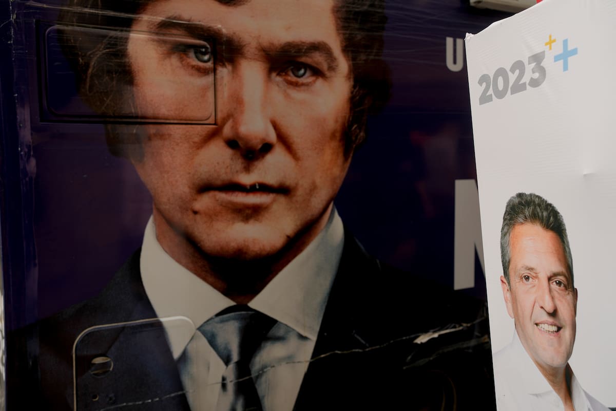 Un colectivo con la imagen de Javier Milei, estacionado junto a un cartel electoral de Sergio Massa, durante el último acto de campaña en Ezeiza