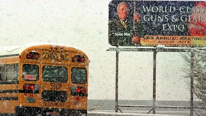 Un colectivo escolar pasa por delante de un cartel publicitario de la reunión anual de la NRA en 1999, tras el tiroteo de Columbine