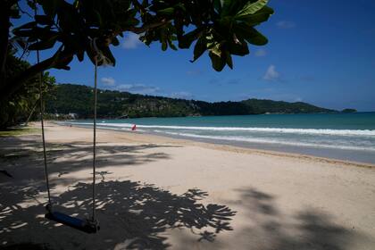 Un columpio vacío cuelga de un árbol en la vacía playa turística de Patong en Phuket, Tailandia, el lunes 28 de junio de 2021. El gobierno de Tailandia comenzará un plan para traer a los turistas de regreso a Phuket a partir del 1 de julio. (AP Foto/Sakchai Lalit)