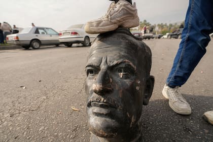 Un combatiente de oposición pone su pie sobre el busto del difunto presidente sirio Hafez Assad en Damasco, Siria, el domingo 8 de diciembre de 2024
