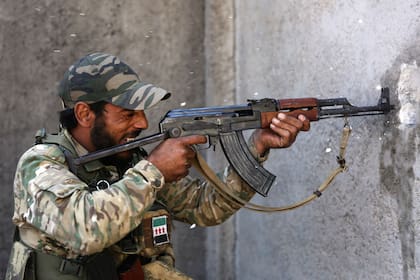 Un combatiente sirio respaldado por Turquía dispara su rifle contra posiciones enemigas, en la ciudad de Ras al-Ain, en el nordeste de Siria