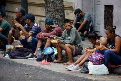 Un comedor comunitario en el barrio de Constitución, en la ciudad de Buenos Aires, donde los asistentes comen en la calle