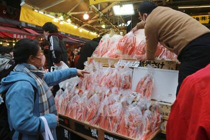 Un comerciante (derecha) vende marisco a una compradora, en Tokio, Japón, el 31 de diciembre de 2021. (AP Foto/Koji Sasahara)