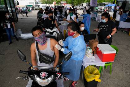 Un conductor de motocicleta recibe una dosis de la vacuna contra el COVID-19 desarrollada por la farmacéutica china Sinovac en un puesto de vacunación en Manila, Filipinas, el 22 de junio de 2021. (AP Foto/Aaron Favila)