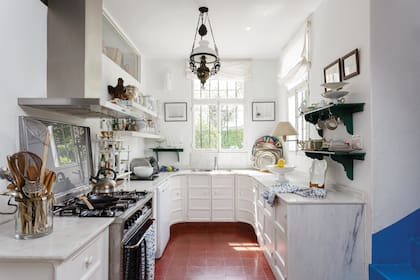 Un detalle maravilloso en esta cocina con un tradicional piso de baldosas color terracota: el enorme mueble curvo con tapa de mármol.