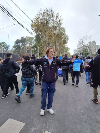 Un "doble" de Charly García, con el bigote bicolor, con chaleco de Defensa Civil, intenta ordenar a la marea humana