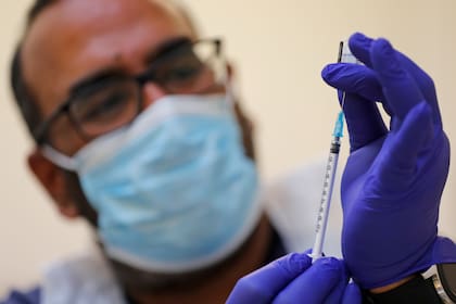 Un doctor se prepara para dar la vacuna de Pfizer/BioNtech contra el coronavirus en un centro de Londres