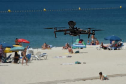 Un drone volado por la policía local advierte a las personas que respeten el distanciamiento social y las medidas de seguridad para evitar nuevos brotes de coronavirus en la playa de Áreas en Sanxenxo, noroeste de España, el 14 de julio de 2020