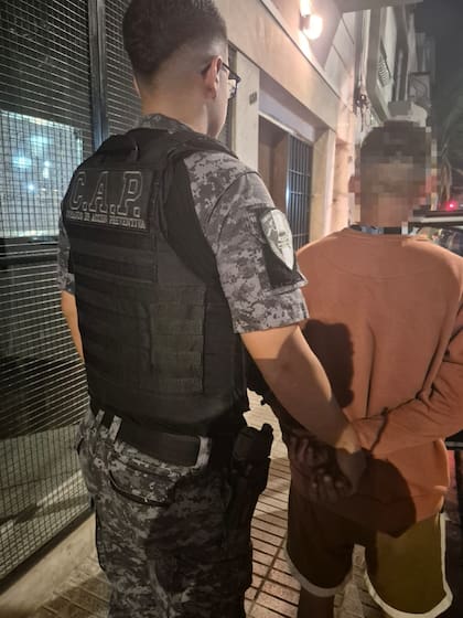 Un efectivo del Cuerpo de Acción Preventiva junto al sospechoso en la vereda del edificio de barrio Alberdi