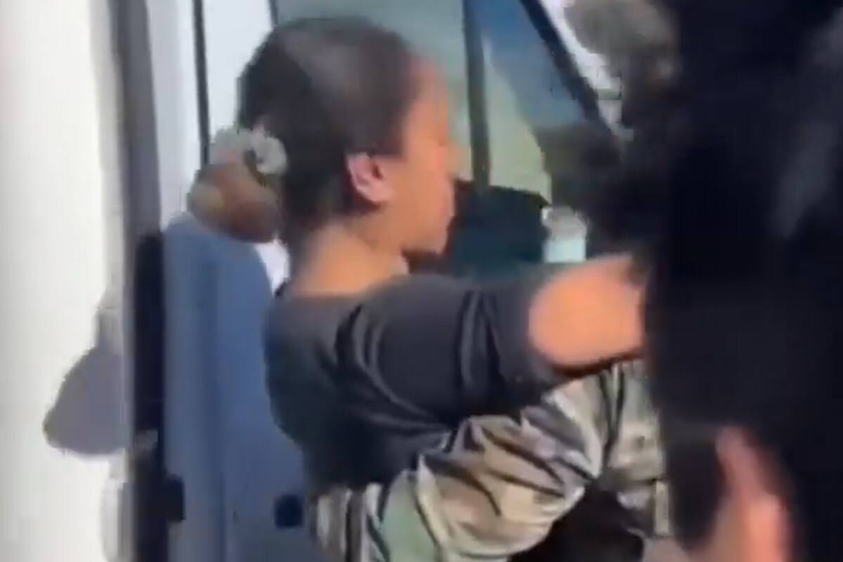 Un efectivo sostiene a la policía al ser hallada en Río Chico, a menos de 1000 metros donde quedó el vehículo varado (Captura de video).