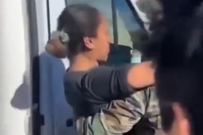 Un efectivo sostiene a la policía al ser hallada en Río Chico, a menos de 1000 metros donde quedó el vehículo varado (Captura de video).