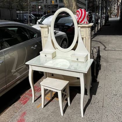 Un elegante dresuar con espejo y banquito espera en una vereda neoyorquina que alguien se lo lleve a su casa