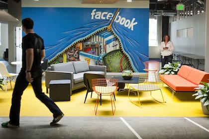 Un empleado camina por uno de los murales decorativos en la oficina de Facebook en Menlo Park, California
