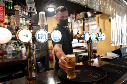 Un empleado de un bar sirve una cerveza en Manchester, Inglaterra, al continuar el levantamiento de restricciones por el coronavirus en el país, el 17 de mayo del 2021. (AP Foto Jon Super)