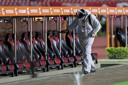 Un empleado desinfecta los bancos de suplente en el estadio Morumbí, de San Pablo; la pelota volvió a rodar en la Copa Libertadores, como si fuera inmune al coronavirus.