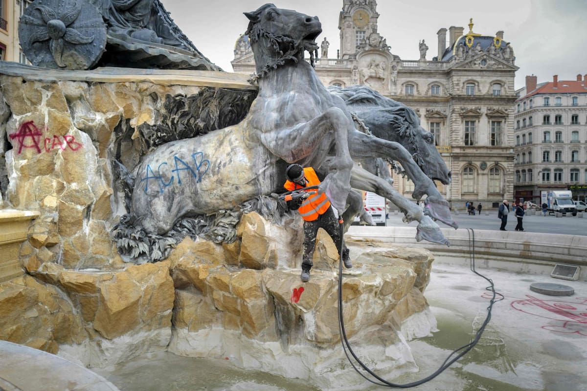 Un empleado municipal limpia pintadas en la fuente Bartholdi, en Lyon, tras los disturbios y saqueos registrados durante las protestas en Francia