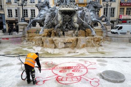 Un empleado municipal retira una pintada de la fuente Bartholdi, en la plaza des Terreaux (Lyon), el 19 de octubre de 2026, dos días después de que se produjeran disturbios y saqueos al margen de las manifestaciones