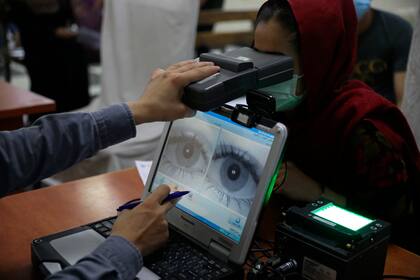 Un empleado toma los datos biométricos a una mujer que tramita su pasaporte en Kabul el 30 de junio del 2021. (AP Photo/Rahmat Gul, File)