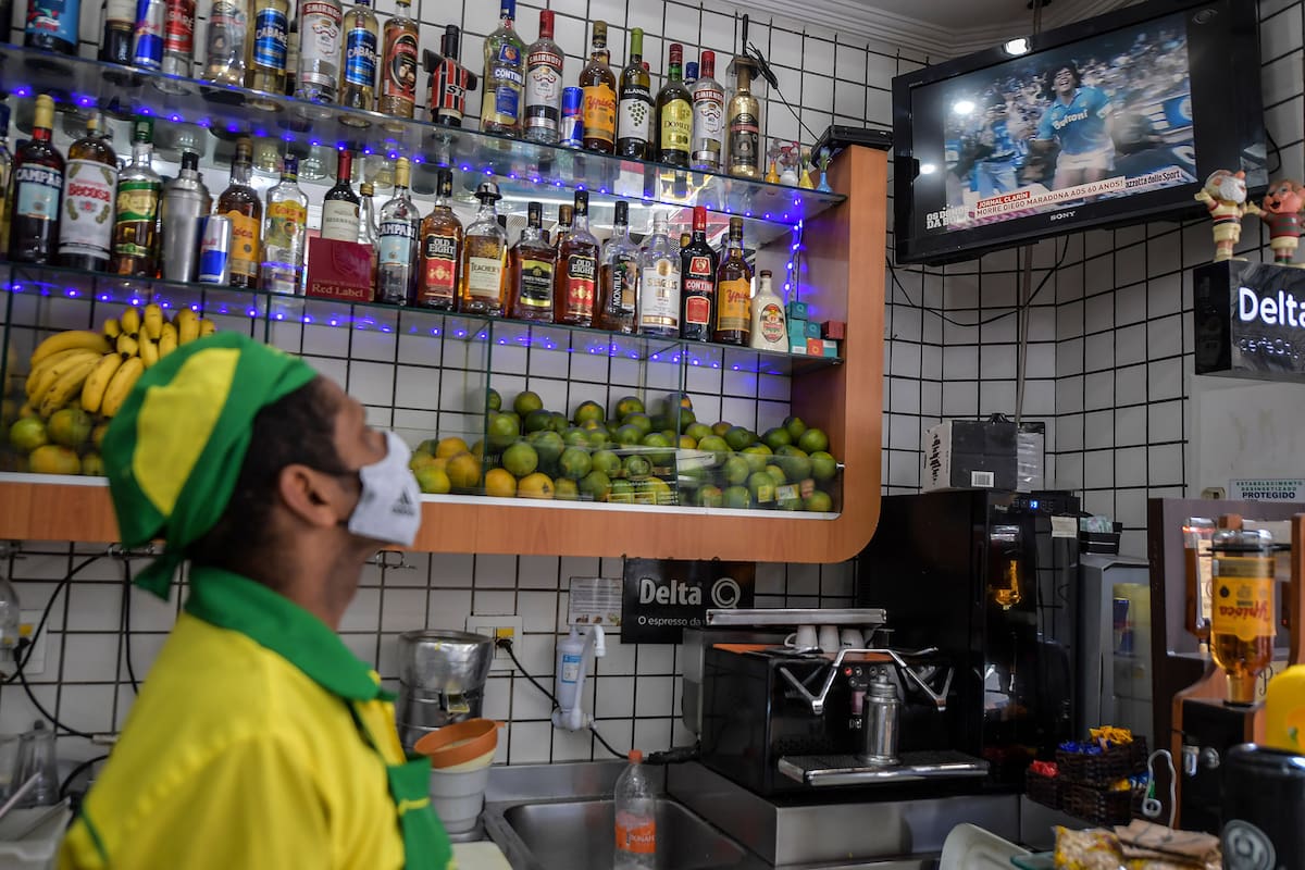 Un empleado ve el anuncio de la muerte de Diego Maradona, ayer, en una pantalla de televisión en un bar en el centro de San Pablo, Brasil