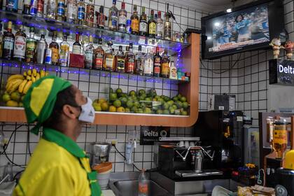 Un empleado ve el anuncio de la muerte de Diego Maradona, ayer, en una pantalla de televisión en un bar en el centro de San Pablo, Brasil