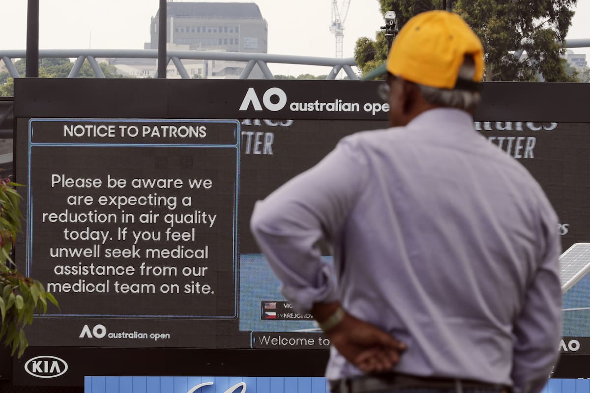 Un espectador lee las noticias relativas al clima: el efecto del humo en Melbourne domina la previa del Australian Open