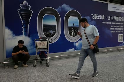 Un extranjero pasa junto a un cartel en el aeropuerto de Baiyun en Guangzhou, en la provincia sureña china de Guangdong, el 6 de noviembre de 2025. (AP Foto/Ng Han Guan)