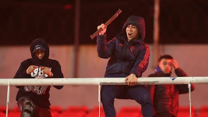 Un fanático de Universidad de Chile sostiene un palo en la parte superior de una de las tribunas