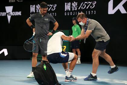 Un asistente ayuda a Caruso a levantarse del suelo mientras Fognini observa.