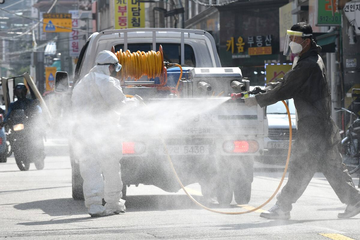 Un funcionario de salud rocía desinfectante en la calle, cerca de la Iglesia Sarang Jeil, donde se detectó un nuevo foco de infección, en Seúl el 18 de agosto de 2020
