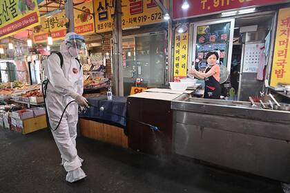 Un funcionario de salud rocía desinfectante en un mercado, cerca de la Iglesia Sarang Jeil, donde se detectó un nuevo foco de infección, en Seúl el 18 de agosto de 2020
