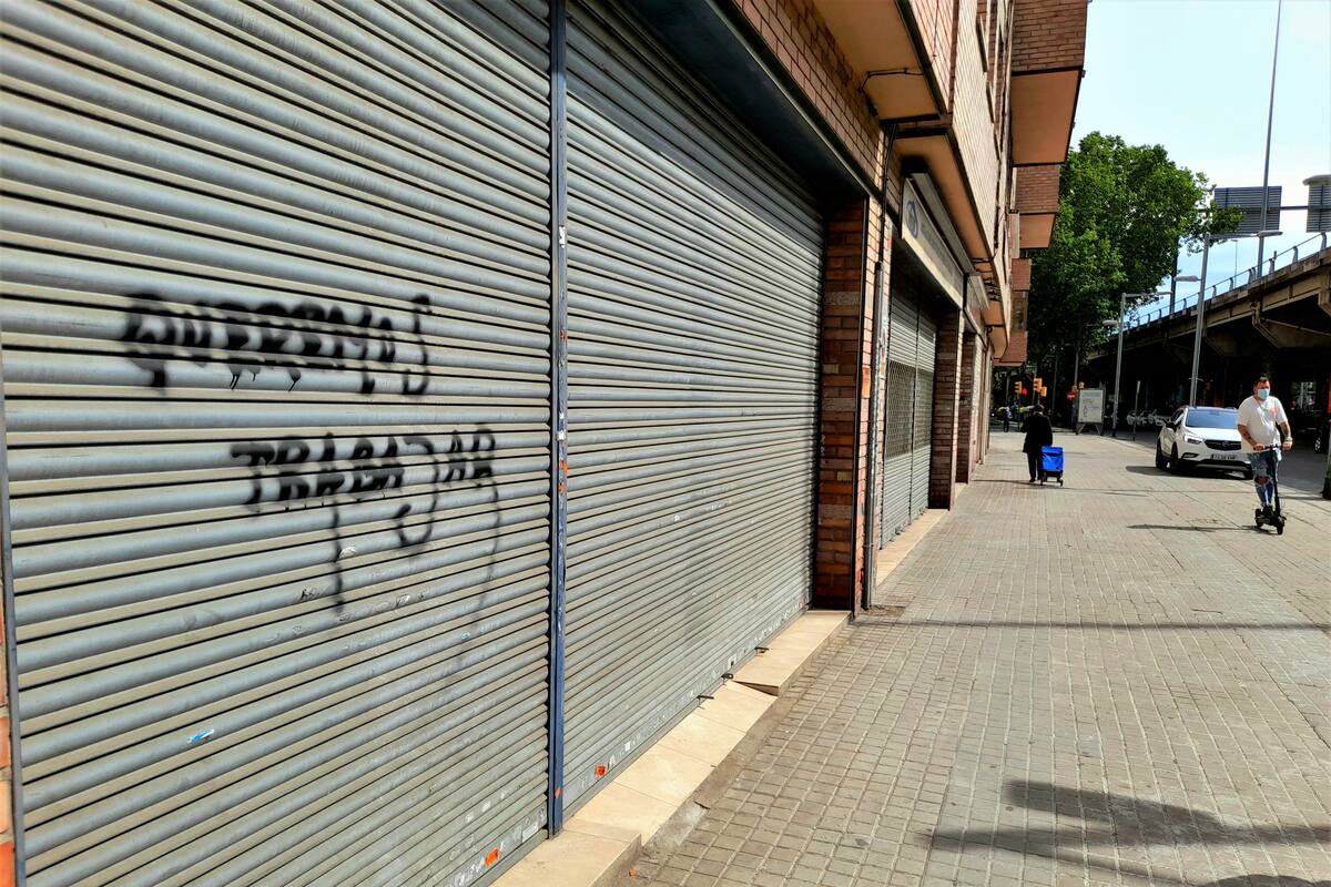 Un grafiti que dice "Queremos trabajar" escrito en la puerta de una tienda cerrada en Sant Adrià