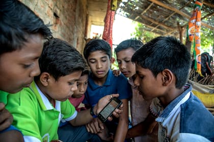 Un grupo de chicos indios escucha música en uno de los celulares provistos por el gobierno