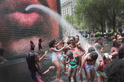 Un grupo de chicos juega con agua, ayer, en un barrio de Chicago, que soportó 46,1°C