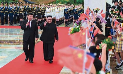 Un grupo de chicos saluda a Xi y Kim con banderas chinas y norcoreanas en la visita de 2020