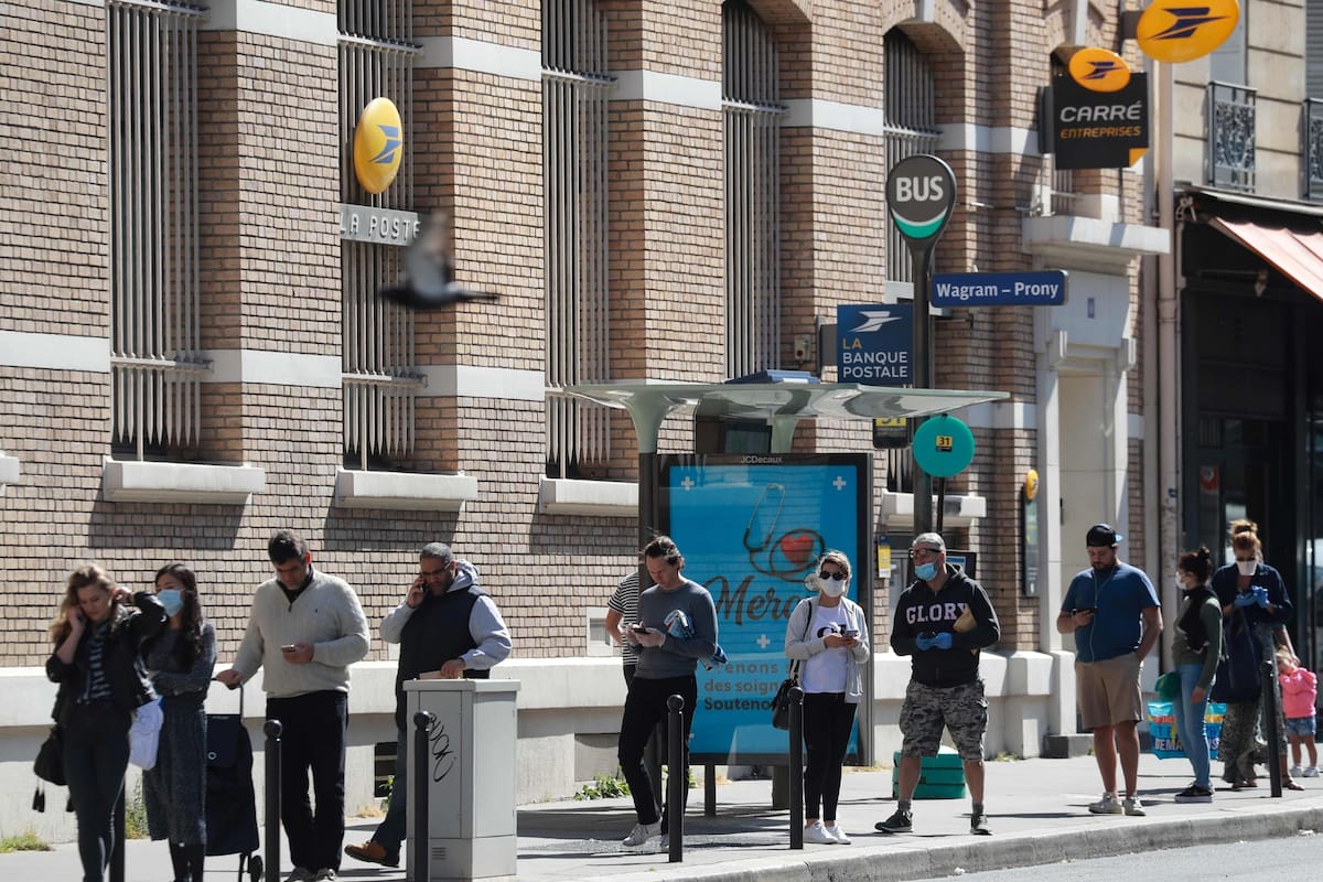 Un grupo de franceses hacen fila frente a una sucursal de correo en París, en el 35° día de confinamiento