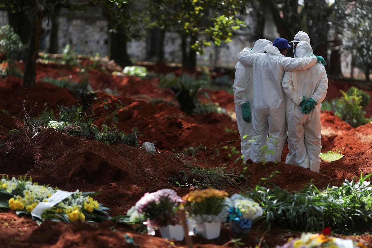 Un grupo de hombres con equipos protectores para protegerse de la Covid-19 entierran y velan a los muertos