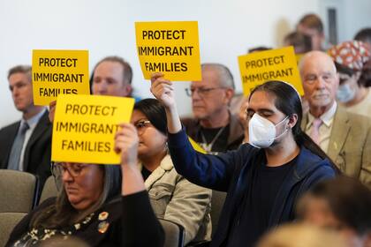 Un grupo de inmigrantes sostiene carteles con mensajes de inclusión en un evento público en Estados Unidos (AP Foto/Gregory Bull)