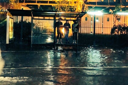 Un grupo de jóvenes se refugia en una parada de colectivos de la avenida Figueroa Alcorta, en Palermo, esta madrugada