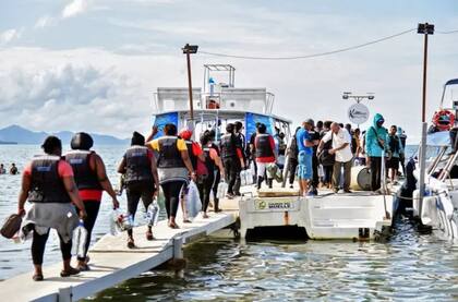 Un grupo de migrantes abordan lanchas en Necoclí, Colombia, para entrar a la selva del Darién y proseguir el recorrido por Panamá.