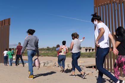 Un grupo de migrantes brasileños cruza por una apertura en la frontera entre Estados Unidos y México, el lunes 8 de junio de 2021, en Yuma, Arizona, para solicitar asilo en Estados Unidos. (AP Foto/Eugene Garcia, archivo)