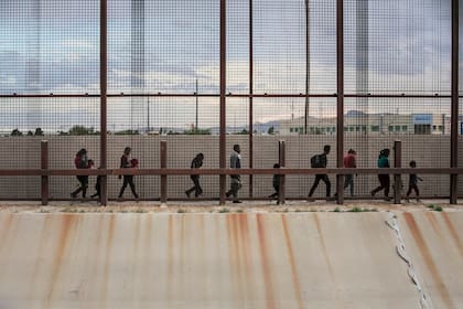 Un grupo de migrantes provenientes de Guatemala camina del lado mexicano de la valla que separa México de los EE.UU, cerca de El Paso, Texas