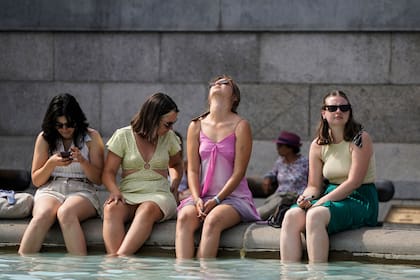 Un grupo de mujeres se refresca sumergiendo sus pies en la fuente de Trafalgar Square, en el centro de Londres