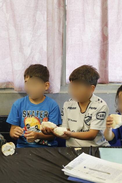 Un grupo de niños comen pan mientras esperan que esté el almuerzo en el comedor Mi Sueño, en Florencio Varela